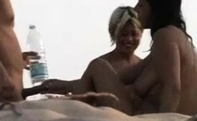 blonde-and-brunette-amateur-milfs-share-a-cock-on-the-beach
